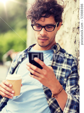 man with smartphone drinking coffee on city street 53986986