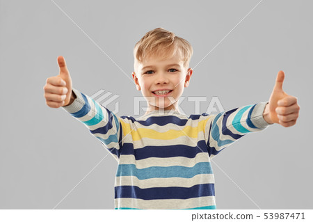 smiling boy in striped pullover showing thumbs up 53987471