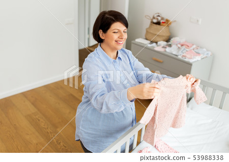 happy pregnant woman setting baby clothes at home happy pregnant woman setting baby clothes at home 53988338