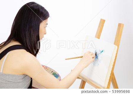 Asian American artist painting on an easel 53995698