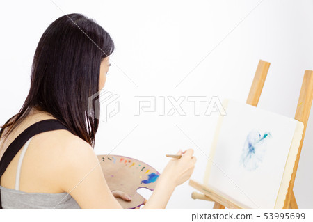 Asian American artist painting on an easel 53995699