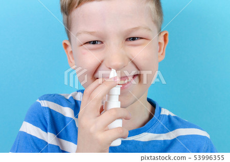 portrait of smiling boy with nasal spray, blue background 53996355