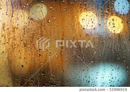 Rain drops on glass window with bokeh background. Rain drops on glass window with bokeh background. 53996919