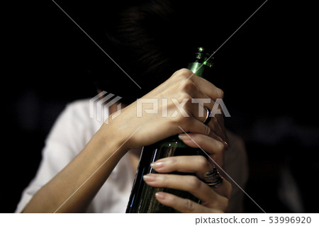 Sad girl holding a bottle of beer in dark Sad girl holding a bottle of beer in dark 53996920