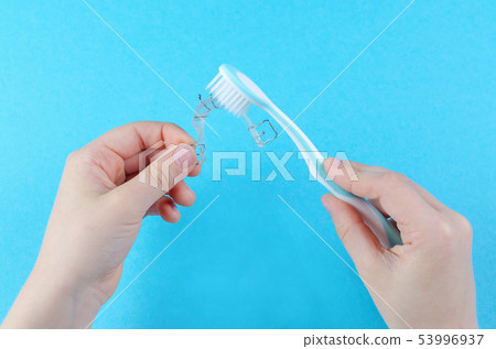 child's hand with orthodontic appliance and toothbrush on blue background 53996937