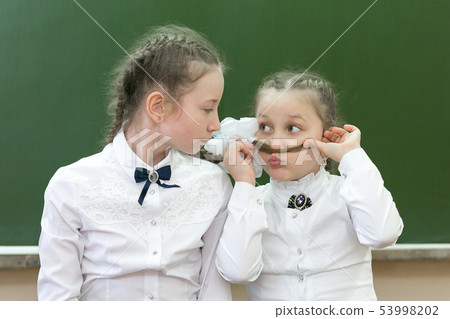 Two sisters at school are laughing at school. Two sisters at school are laughing at school. 53998202