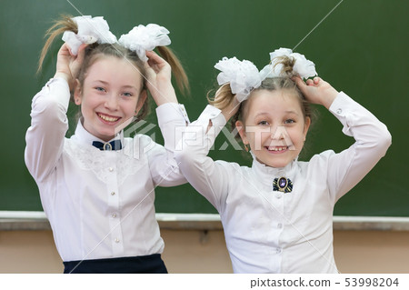 Two sisters at school are laughing at school. 53998204