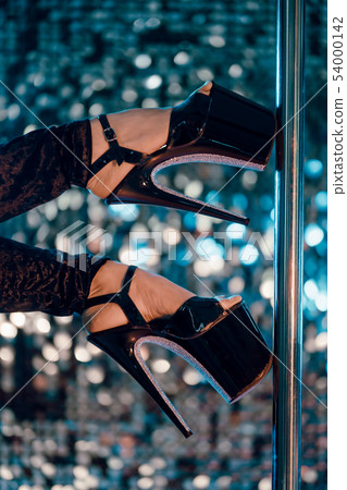 Heels of sexy woman pole dancing or striptease with pylon in night club. Heels of sexy woman pole dancing or striptease with pylon in night club. 54000142
