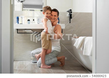 Smiling father and son staying in bathroom at home Smiling father and son staying in bathroom at home 54000423