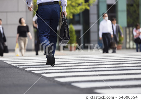 A back view of a businessman crossing a pedestrian crossing A back view of a businessman crossing a pedestrian crossing 54000554