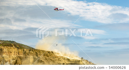Helicopter in flight on cloudy sky above a cliff Helicopter in flight on cloudy sky above a cliff 54000626