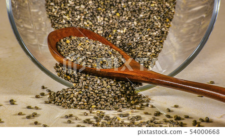 Glass container and wooden spoon with chia seeds Glass container and wooden spoon with chia seeds 54000668