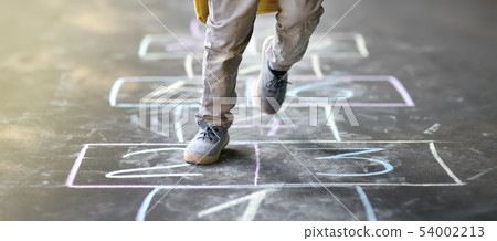 Closeup of little boy's legs and hopscotch drawn 54002213