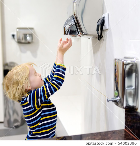 Little caucasian boy drying his hands in a Little caucasian boy drying his hands in a 54002390