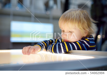 Little ?aucasian boy is looking an exposition in a Little ?aucasian boy is looking an exposition in a 54002994