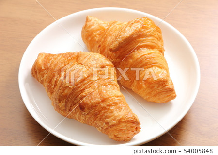 兩個羊角麵包放在圓盤中。早餐和小吃的圖像。 54005848