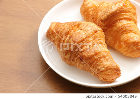 兩個羊角麵包放在圓盤中。早餐和小吃的圖像。 54005849