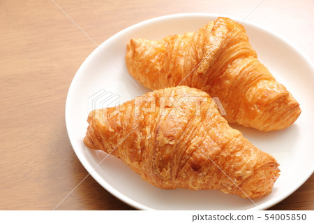 兩個羊角麵包放在圓盤中。早餐和小吃的圖像。 54005850