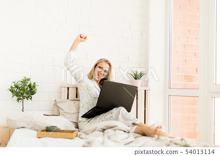 Happy excited woman working on a laptop at home Happy excited woman working on a laptop at home 54013114