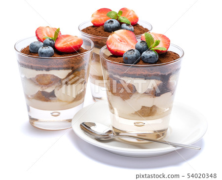 Classic tiramisu dessert with blueberries and strawberries in a glass isolated on a white background Classic tiramisu dessert with blueberries and strawberries in a glass isolated on a white background 54020348