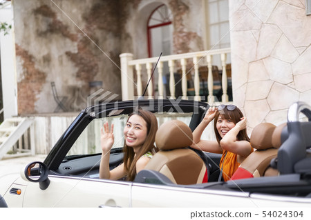 兩個漂亮的女人在開放的汽車中打開汽車到豪華住宅區的朋友家 兩個漂亮的女人在開放的汽車中打開汽車到豪華住宅區的朋友家 54024304