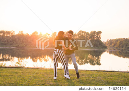 Romantic, social dance and people concept - young couple dancing bachata on the background of sunset Romantic, social dance and people concept - young couple dancing bachata on the background of sunset 54029134
