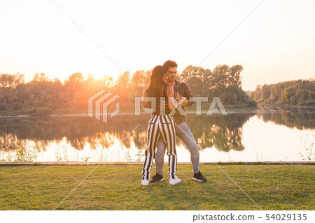 Romantic, social dance, people concept - young couple dancing bachata near the lake in sunny day Romantic, social dance, people concept - young couple dancing bachata near the lake in sunny day 54029135