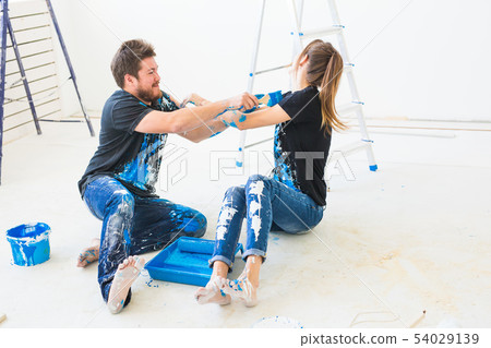 Redecoration, color, renovation and people concept - couple going to paint the wall, they are mixing Redecoration, color, renovation and people concept - couple going to paint the wall, they are mixing 54029139