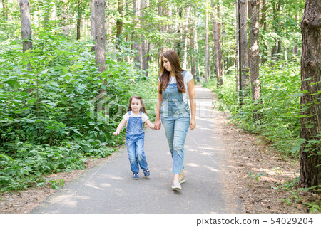 Family, children and nature concept - Portrait of attractive woman and little child girl walking 54029204