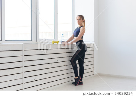 People, healthy and sport concept - Portrait of fitness woman with bottle of water and dumbbells 54029234