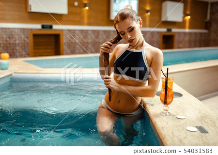 Woman with fruit cocktail at the pool side indoors 54031583