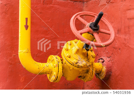 yellow pipeline with valve against the red wall 54031936