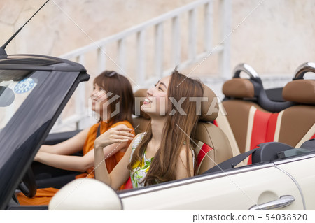 Two pretty women traveling on a women's trip that goes up in a stylish breeze with a pleasant breeze to ride an open car Two pretty women traveling on a women's trip that goes up in a stylish breeze with a pleasant breeze to ride an open car 54038320