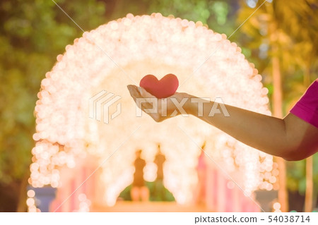 Female hand with a little red heart shape pillow Female hand with a little red heart shape pillow 54038714