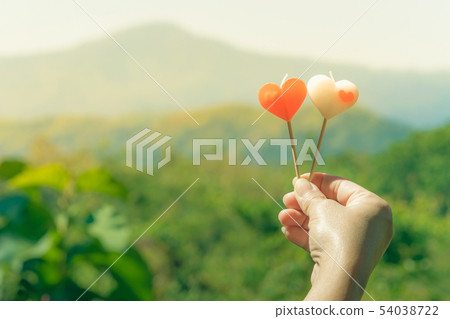 Two heart shape candles in female hand Two heart shape candles in female hand 54038722
