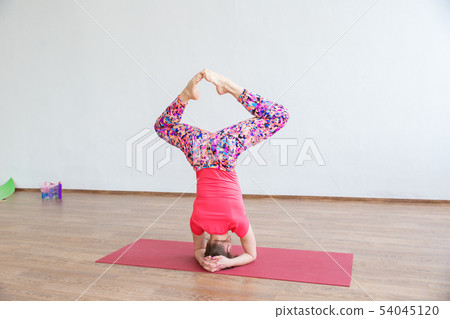 A young girl performs acrobatics while standing on his head. A young girl performs acrobatics while standing on his head. 54045120