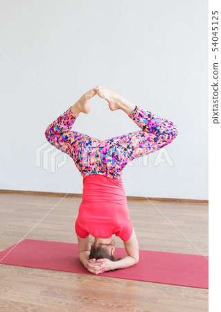 A young girl performs acrobatics while standing on his head. A young girl performs acrobatics while standing on his head. 54045125