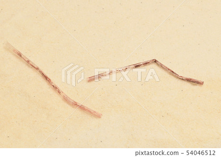 Plastic waste straw on sandy beach 54046512