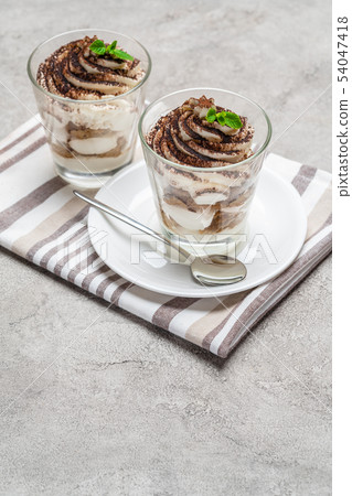 Classic tiramisu dessert in a glass on concrete background Classic tiramisu dessert in a glass on concrete background 54047418