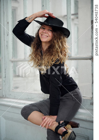 fashionable girl dressed in black shirt, hat and 54048738