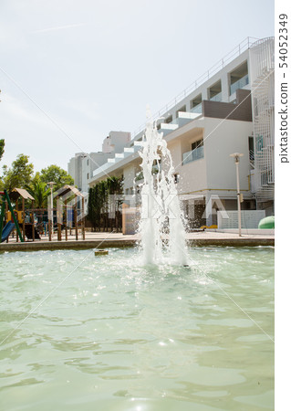 Fountain and white walled resort mansion by the coast of Majorca Island 54052349