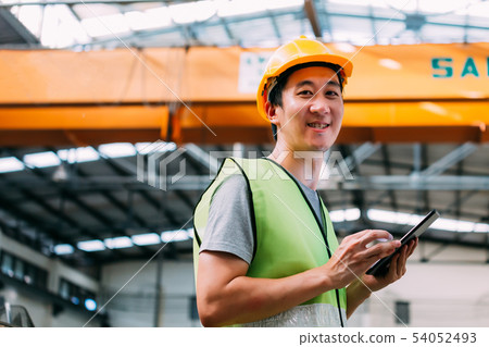 Young Asian male factory worker holding a digital tablet Young Asian male factory worker holding a digital tablet 54052493