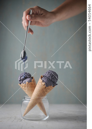 Delicious purple ice cream cone and pouring sauce 54054664
