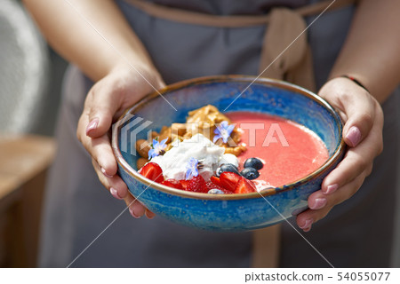 Morning breakfast in a blue plate in the hands of a waitress. fresh blueberry smoothies for 54055077