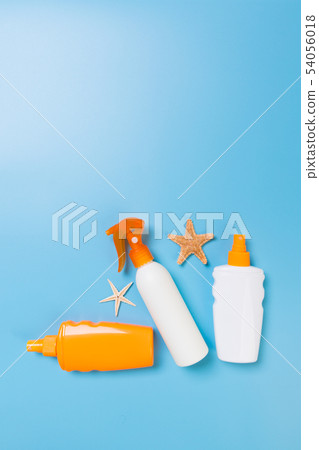 Sunscreen bottles with seashells on blue table top Sunscreen bottles with seashells on blue table top 54056018