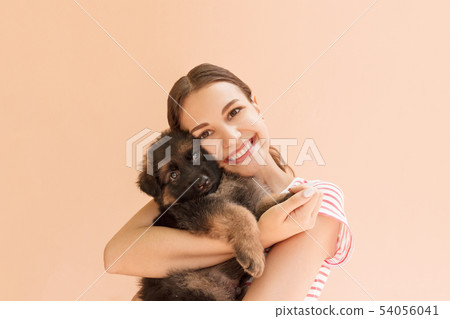 Young woman enjoys hugging a small cute puppy Young woman enjoys hugging a small cute puppy 54056041