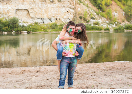 Festival holi, summer tourism and nature concept - young attractive girl sitting piggyback on her 54057272