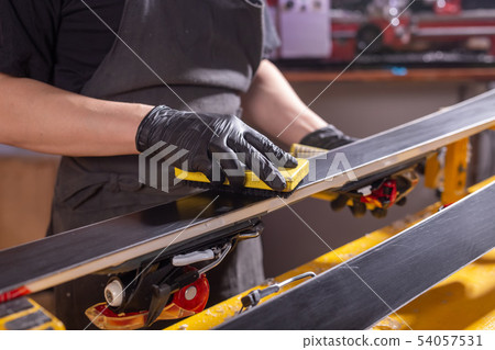 A man repairman in workshop ski service repairing the ski 54057531