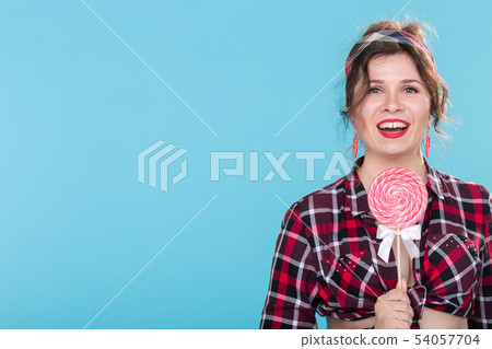 Diet, dessert and junk food - woman pin-up style with lollipop over the blue background copy space. Diet, dessert and junk food - woman pin-up style with lollipop over the blue background copy space. 54057704