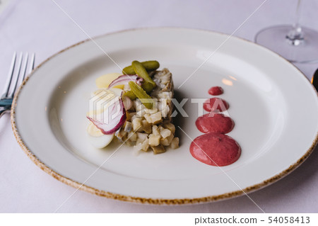 Restaurant delicacy dish on a purple tablecloth. White plate with herring 54058413